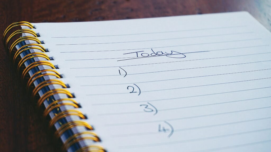 A close-up view of a handwritten to-do list on a spiral notebook with numbers for tasks.